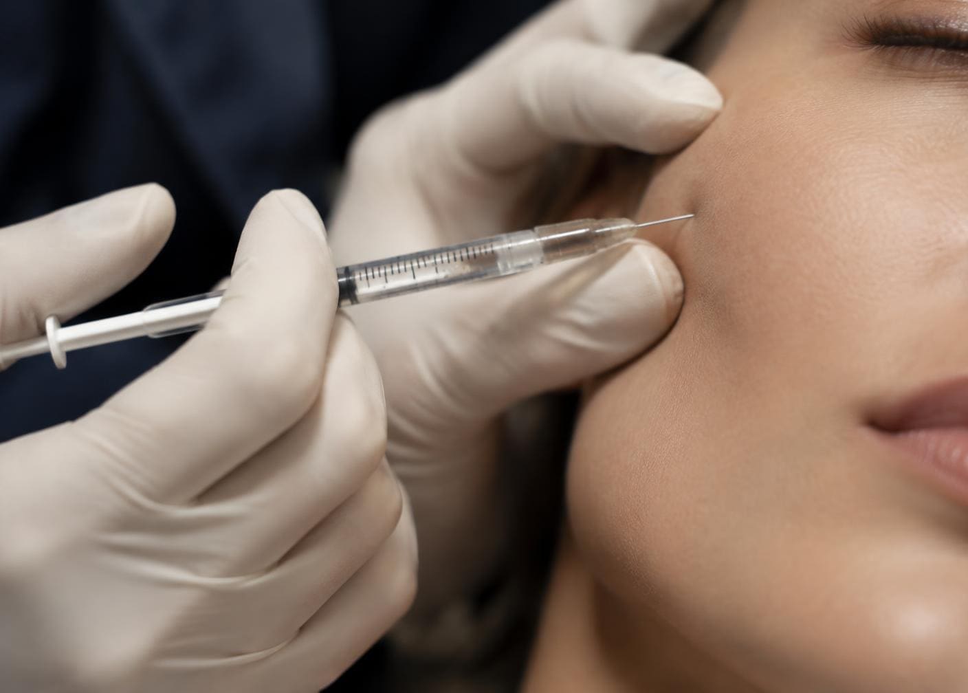 Close-up of gloved hands stabilised against a patient's cheek with a fine needle at a controlled angle
