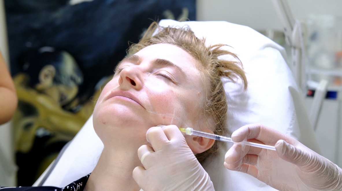Professional aesthetic practitioner performing masseter Botox treatment on patient in clinical setting