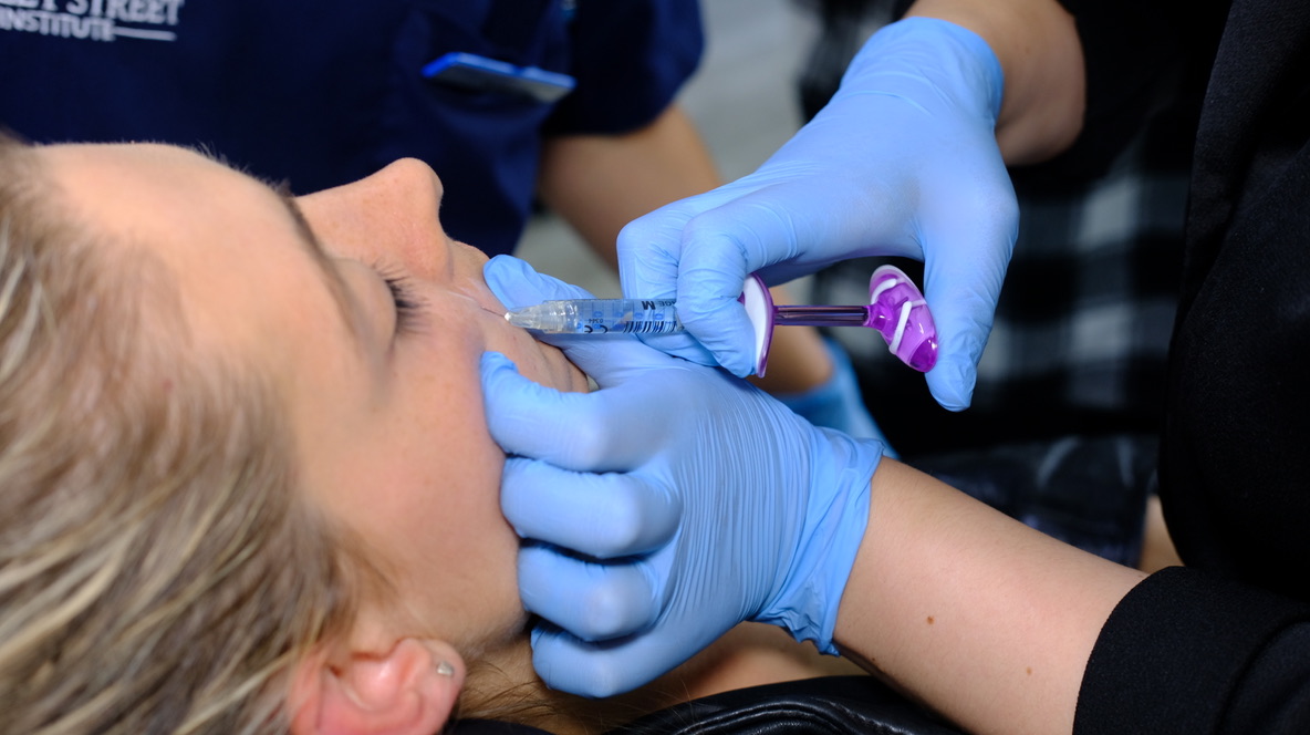 Professional demonstrating proper hand positioning for stable aesthetic injections with gauze placement and support techniques